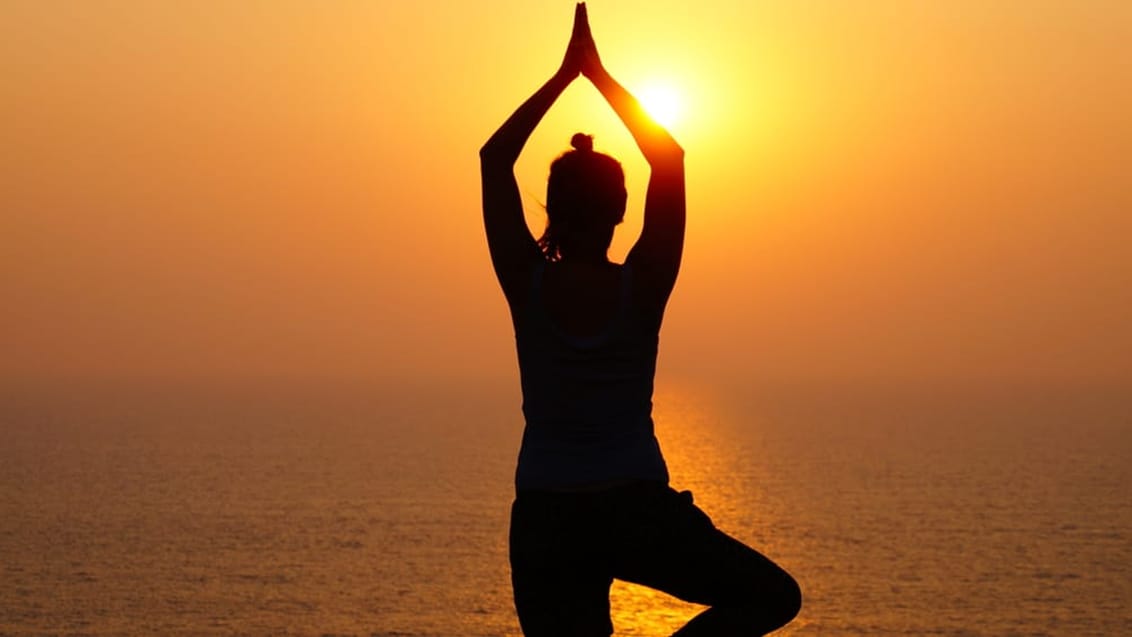 Yoga over havet ved solnedgang