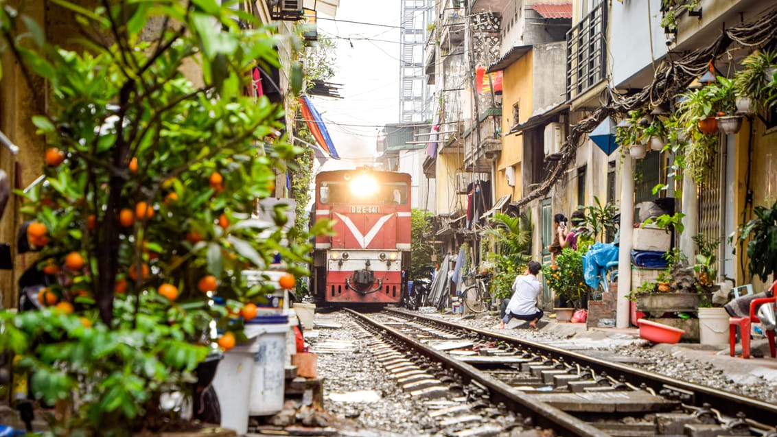 Tog kører gennem små gader i Hanoi