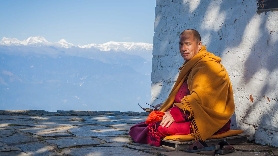 En enlig munk vogter ved Lungchotse Gompa med udsigt over Himalaya-bjergene