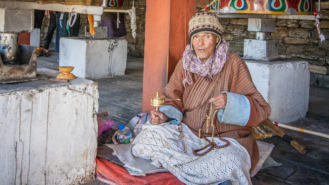 En ældre mand med sin bedemølle i Thimphu