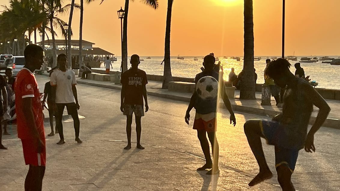 Drenge spiller fodbold ved kysten i Stone Town på Zanzibar